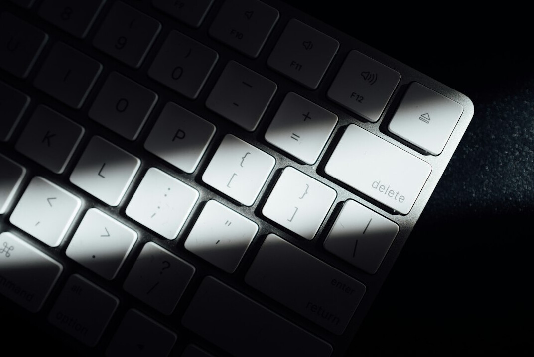 Close-up of hands typing on a laptop keyboard with code on screen